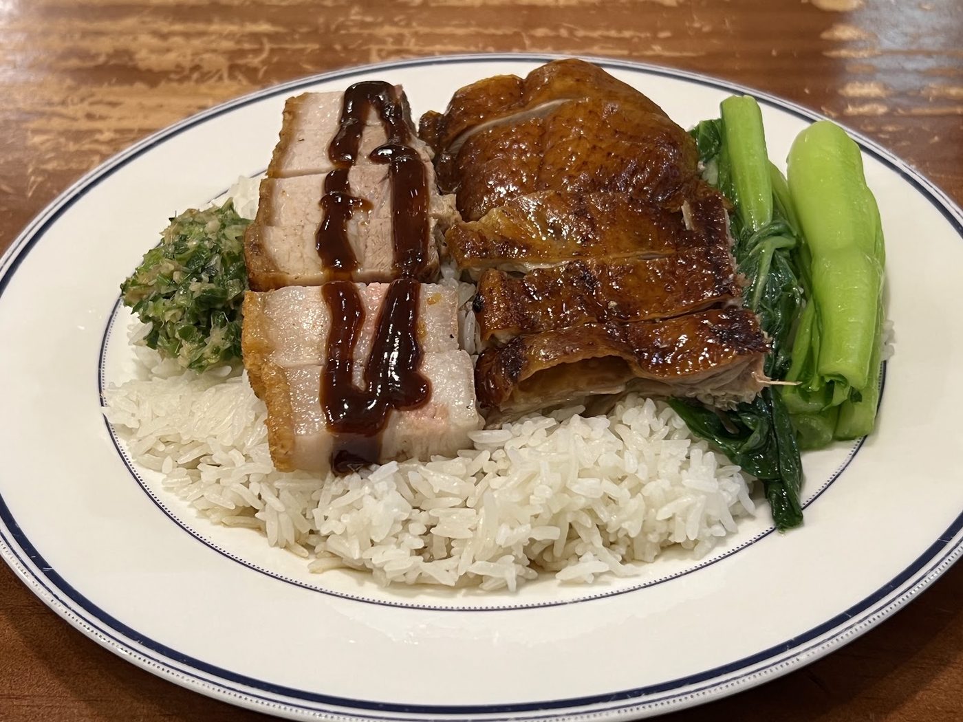 Roast duck and crispy pork belly over rice with greens